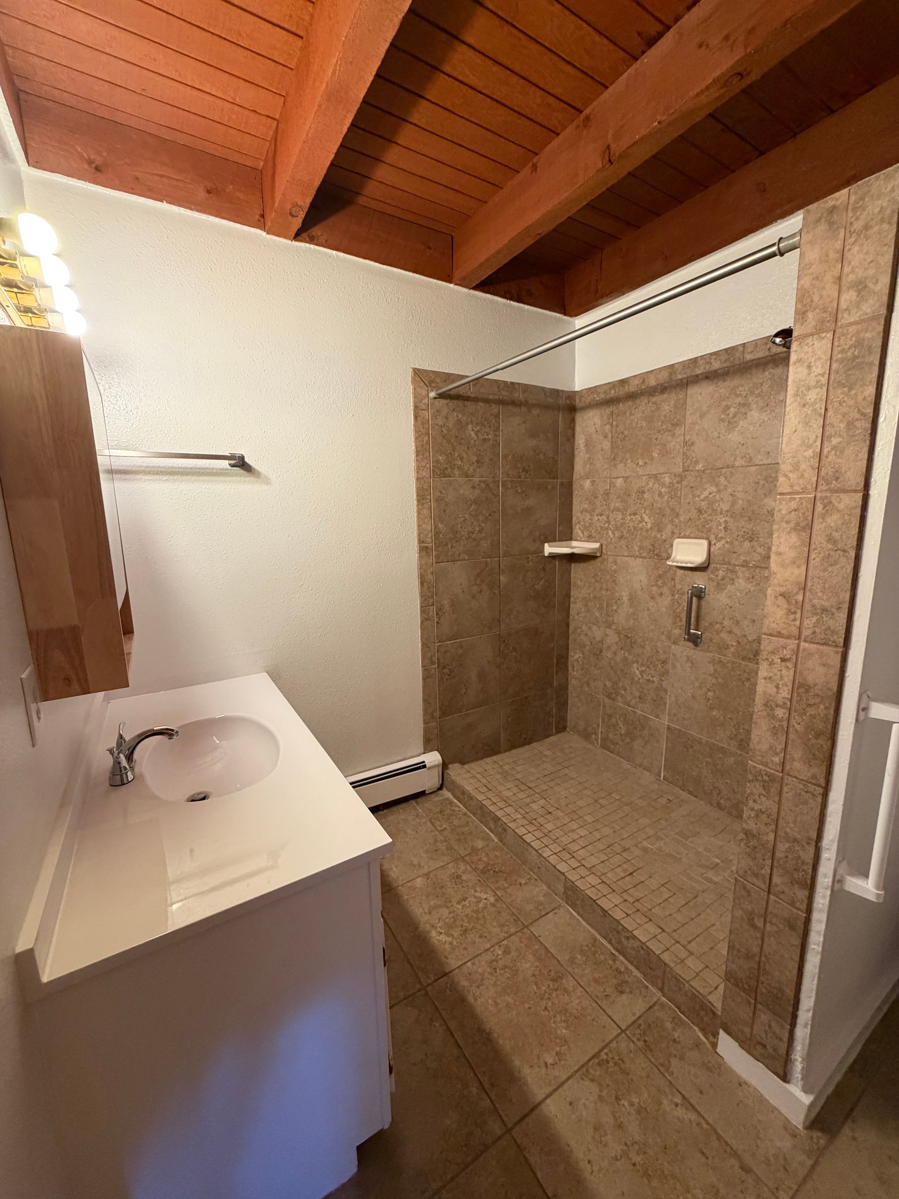 Modern bathroom with walk-in tiled shower and wood beam accents