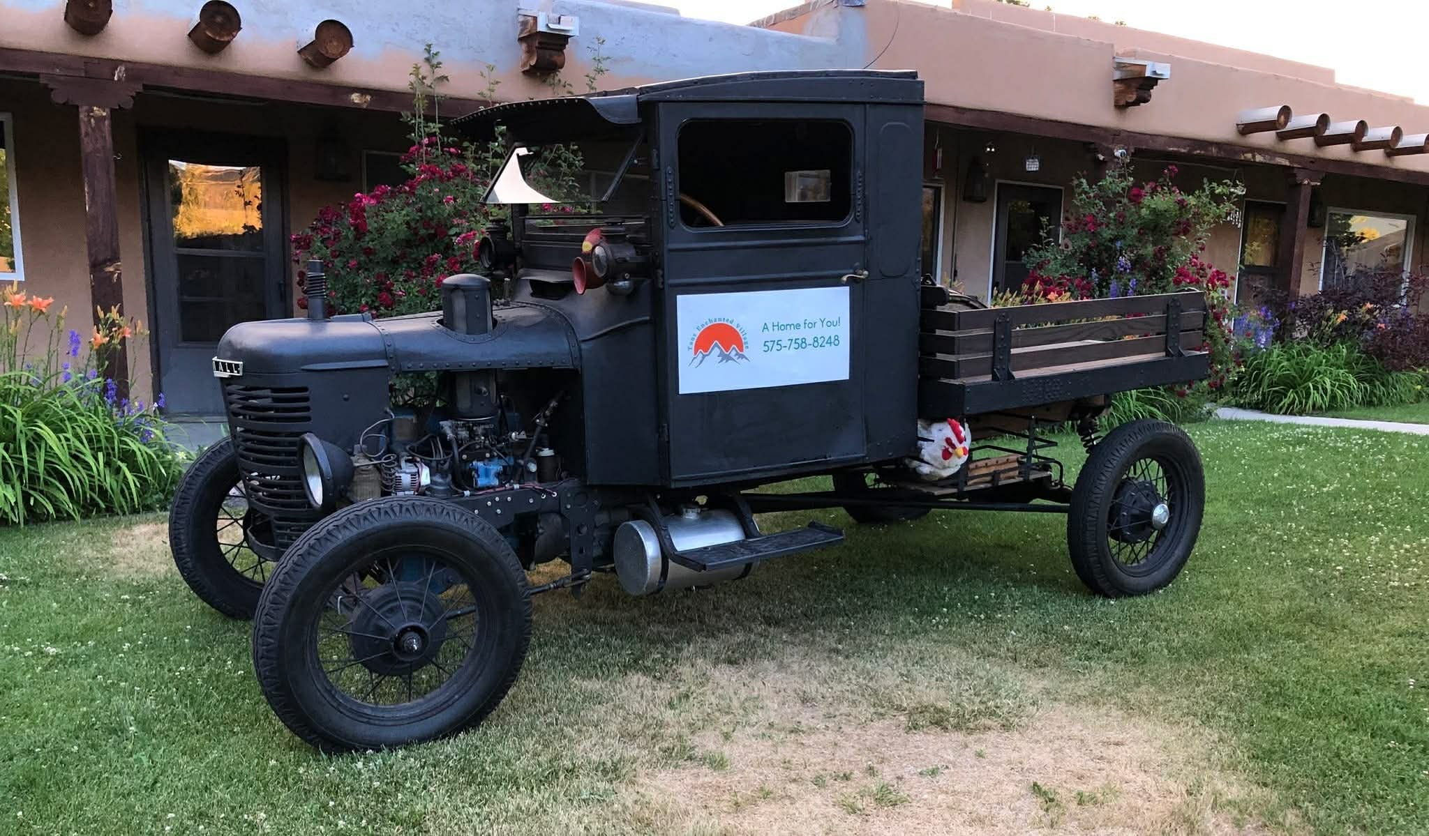 Vintage truck on the community grounds with adobe buildings and gardens in the background