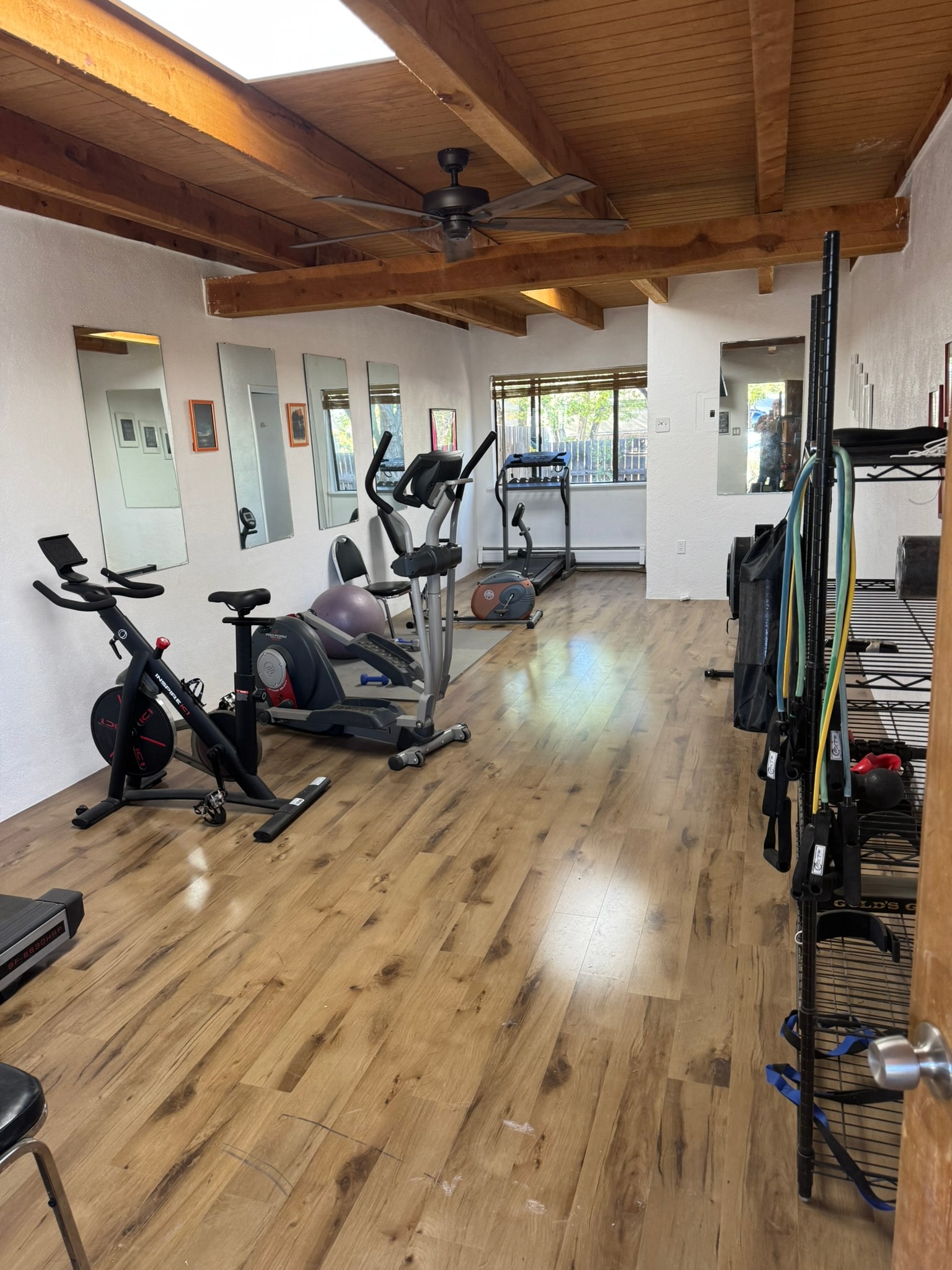 On-site fitness room with cardio equipment, mirrors, and wood beam ceiling