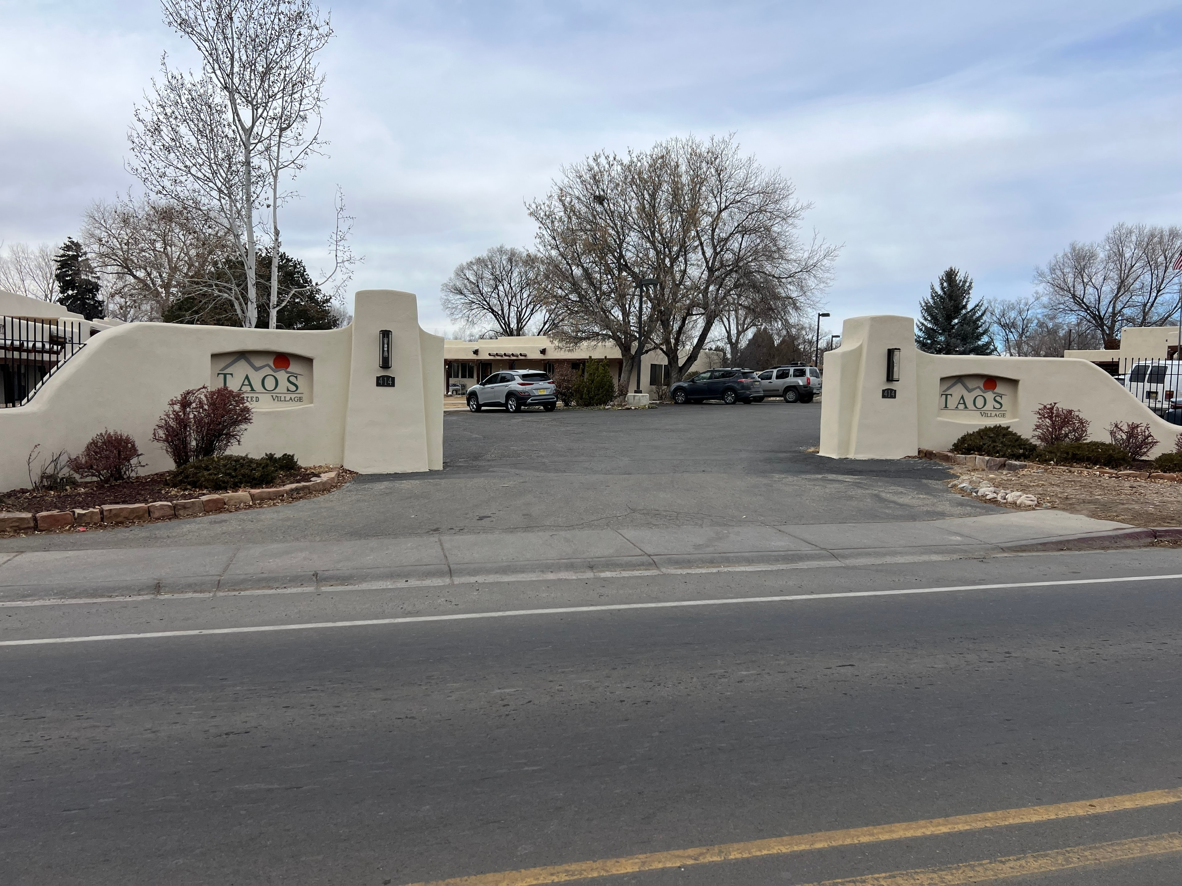 Grand entrance to Taos Enchanted Village with adobe pillars and community signage